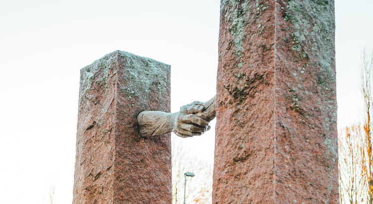 Ett konstverk i Södra Ryd. Två stolpar som har händer och skakar hand med varandra 